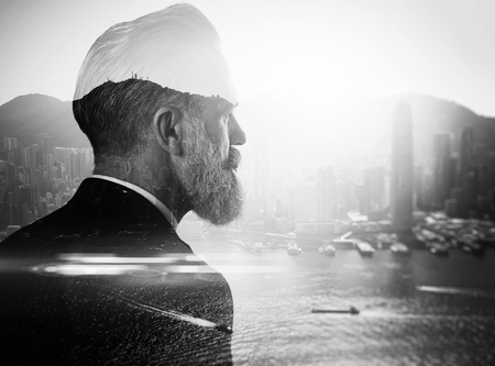 50792310 - stylish businessman in a suit looking at the horizon. photo of double exposure of the city. black and white